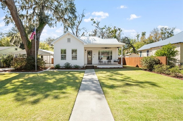 bungalow featuring ceiling fan, a front lawn, fence, covered porch, and metal roof