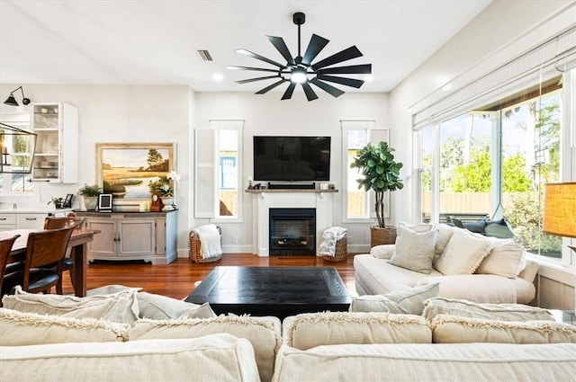 living room featuring a fireplace, dark wood-style floors, visible vents, and baseboards