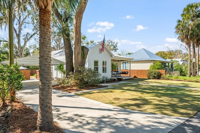 view of front facade featuring a front lawn, a ceiling fan, fence, and driveway