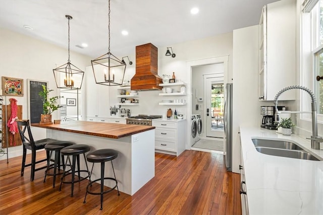 kitchen with premium range hood, separate washer and dryer, freestanding refrigerator, wood counters, and a sink