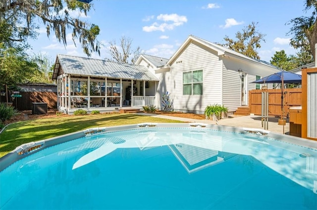 rear view of property with fence, a lawn, and metal roof