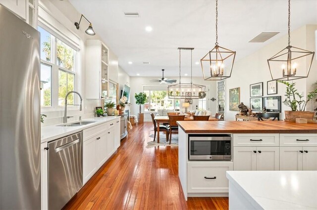 kitchen featuring a sink, white cabinets, wooden counters, and stainless steel appliances