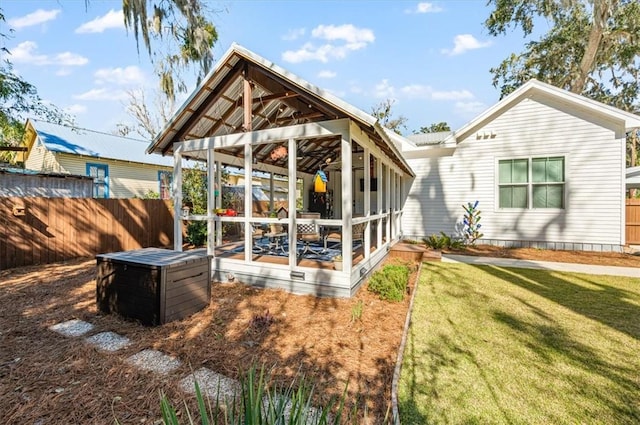 back of property with a yard, fence, and a sunroom