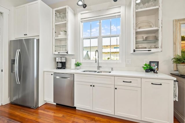 kitchen with a sink, white cabinets, glass insert cabinets, and stainless steel appliances