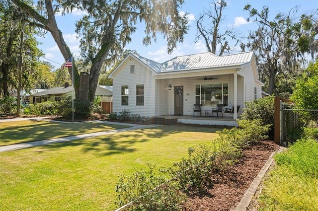 view of front of property featuring metal roof, a front lawn, a ceiling fan, and fence