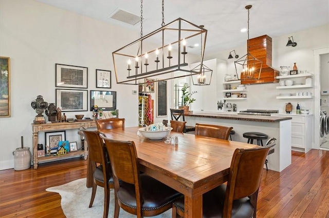 dining space with visible vents, baseboards, dark wood-type flooring, and washer and clothes dryer