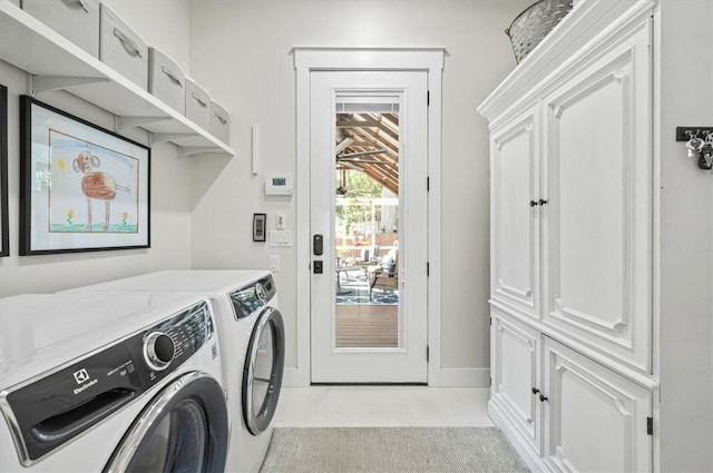 washroom featuring baseboards, cabinet space, and washing machine and dryer