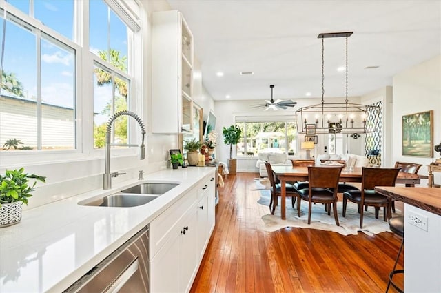 kitchen featuring a sink, hardwood / wood-style flooring, white cabinets, light countertops, and stainless steel dishwasher