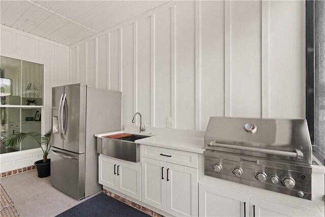 kitchen with stainless steel refrigerator with ice dispenser, a sink, light countertops, and white cabinets
