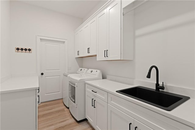 clothes washing area featuring cabinet space, washer and clothes dryer, and light wood finished floors