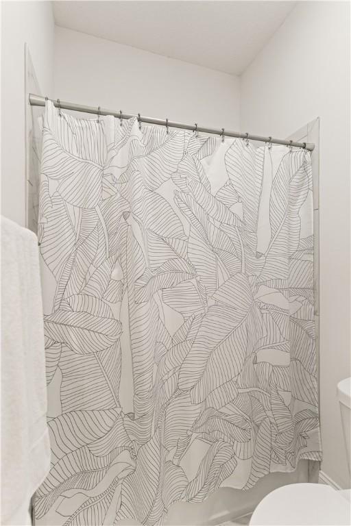 bathroom with toilet and a shower with curtain