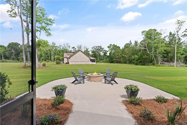 surrounding community featuring an outdoor fire pit, a patio, a lawn, and view of wooded area