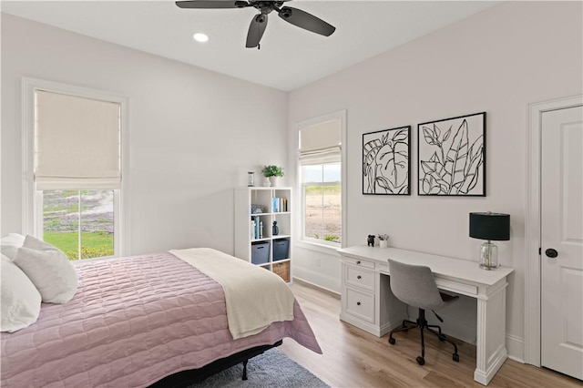 bedroom with multiple windows, light wood-style flooring, an office area, and baseboards