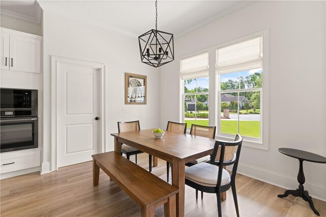 dining area with ornamental molding, a chandelier, light wood-style flooring, plenty of natural light, and baseboards