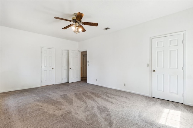 unfurnished bedroom with ceiling fan, carpet floors, visible vents, baseboards, and two closets