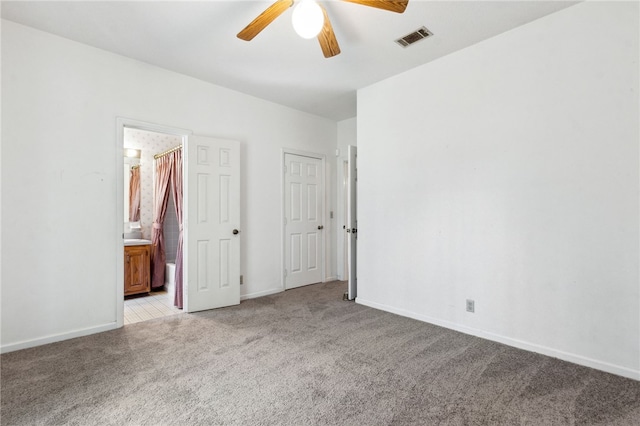 unfurnished bedroom featuring light colored carpet, visible vents, ceiling fan, ensuite bath, and baseboards