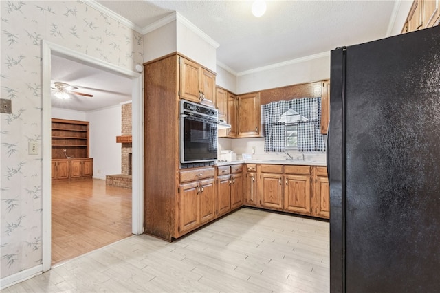 kitchen with light wood-type flooring, black appliances, crown molding, and wallpapered walls