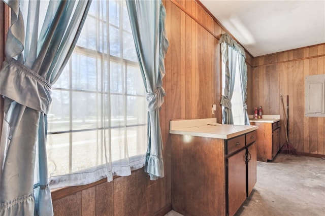 kitchen featuring plenty of natural light, wooden walls, brown cabinets, and light countertops