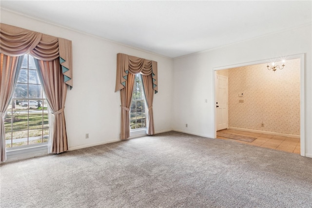 carpeted empty room featuring a chandelier and baseboards