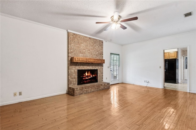 unfurnished living room featuring visible vents, crown molding, a textured ceiling, and light wood finished floors