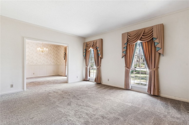 spare room featuring ornamental molding, carpet, and an inviting chandelier