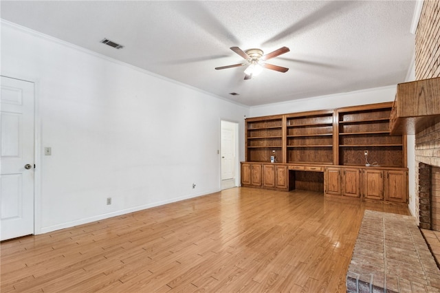 unfurnished living room with visible vents, light wood-style flooring, ornamental molding, built in study area, and a textured ceiling