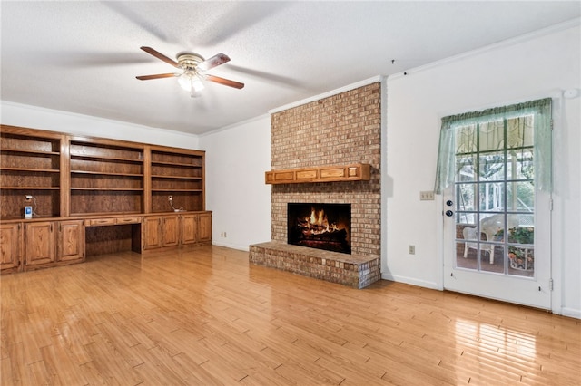 unfurnished living room featuring a brick fireplace, light wood-style flooring, ornamental molding, and built in desk