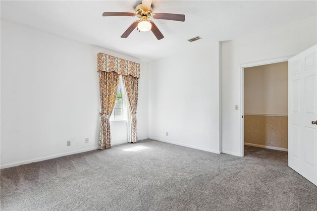 carpeted spare room featuring visible vents, ceiling fan, and baseboards