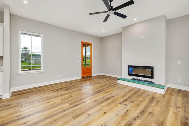 225 Water Crest Dr, Brunswick, GA 31523 - unfurnished living room with light wood-type flooring, baseboards, ceiling fan, a glass covered fireplace, and recessed lighting