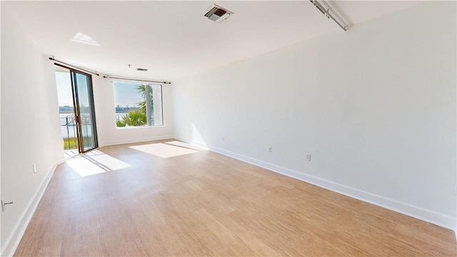 empty room with visible vents, baseboards, light wood-style floors, and expansive windows