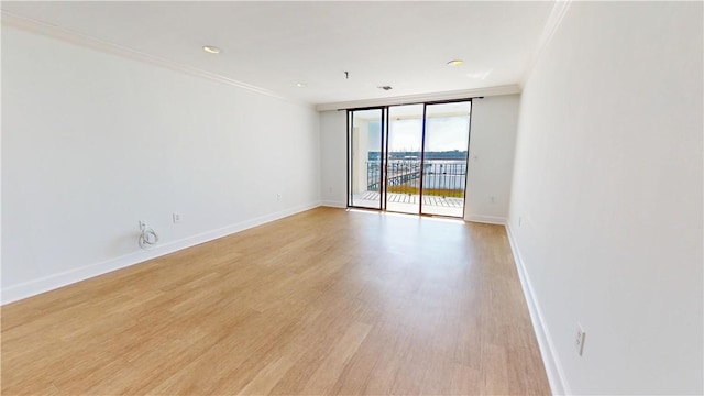 empty room with crown molding, baseboards, light wood-type flooring, expansive windows, and recessed lighting