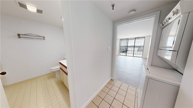 bathroom featuring vanity, visible vents, tile patterned flooring, stacked washer and clothes dryer, and toilet