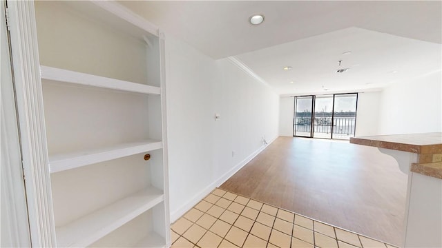 spare room featuring visible vents, baseboards, a wall of windows, ornamental molding, and recessed lighting