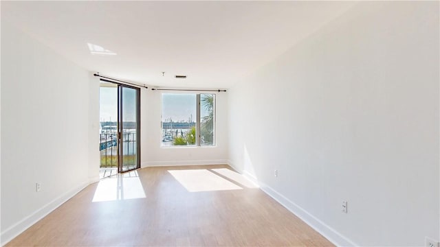 spare room featuring visible vents, wood finished floors, and baseboards