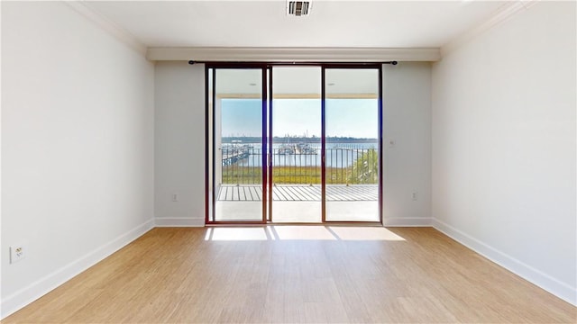 unfurnished room featuring wood finished floors, visible vents, and baseboards