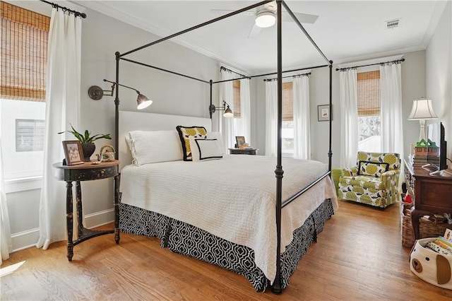 bedroom with visible vents, ornamental molding, ceiling fan, and wood finished floors