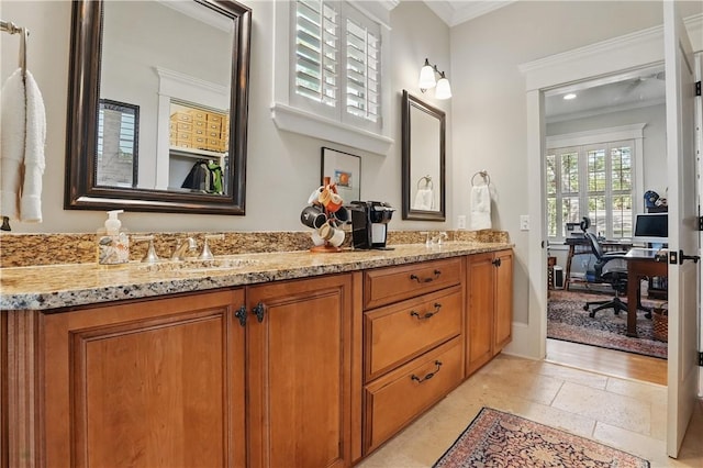 bathroom with double vanity, ornamental molding, a sink, and stone tile floors
