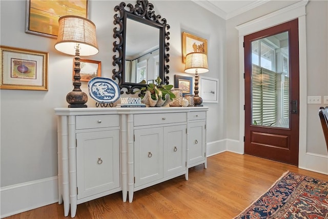 foyer entrance with baseboards, light wood-style flooring, and ornamental molding