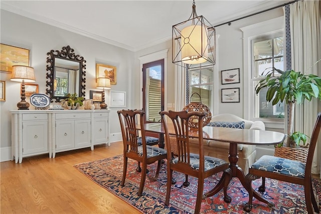 dining space with crown molding and light wood-style flooring