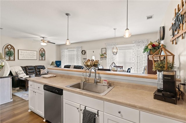 kitchen featuring stainless steel dishwasher, a sink, open floor plan, white cabinetry, and light wood-type flooring