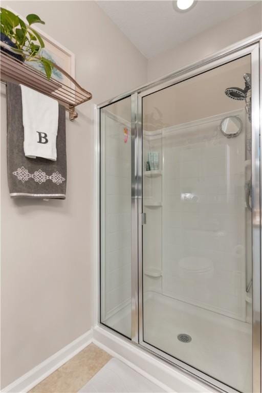 bathroom featuring a shower stall, tile patterned floors, and baseboards
