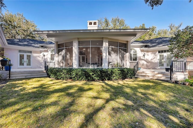 back of house with a yard, a sunroom, and french doors