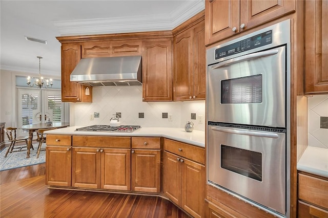 kitchen with appliances with stainless steel finishes, extractor fan, crown molding, pendant lighting, and an inviting chandelier