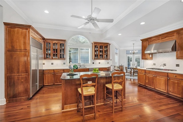 kitchen with appliances with stainless steel finishes, a kitchen breakfast bar, tasteful backsplash, extractor fan, and a center island