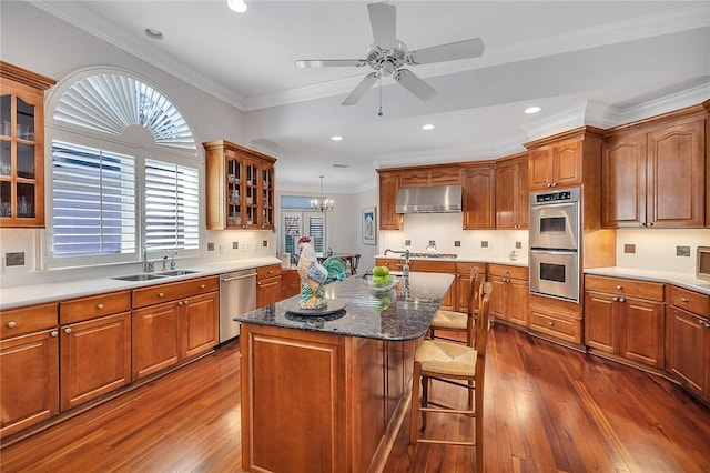 kitchen with ornamental molding, stainless steel appliances, sink, pendant lighting, and a kitchen island