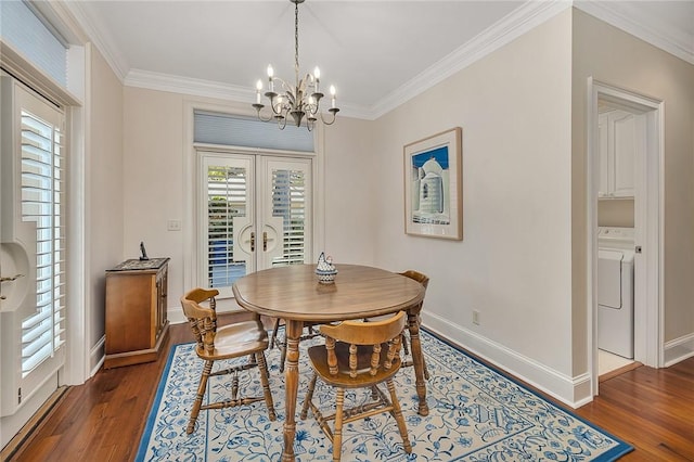 dining room featuring washer / dryer, ornamental molding, dark wood-type flooring, and a chandelier