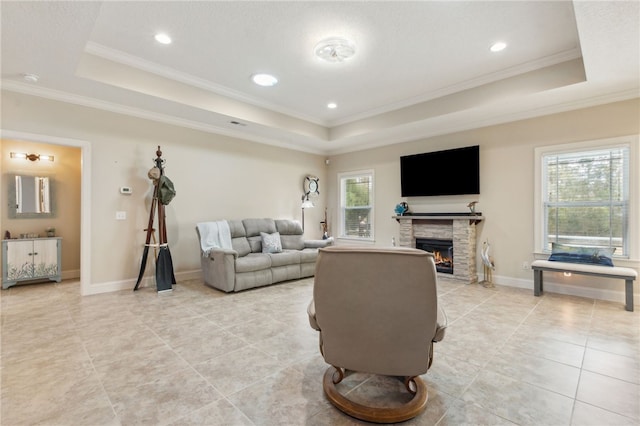 tiled living room featuring a raised ceiling, crown molding, and a stone fireplace