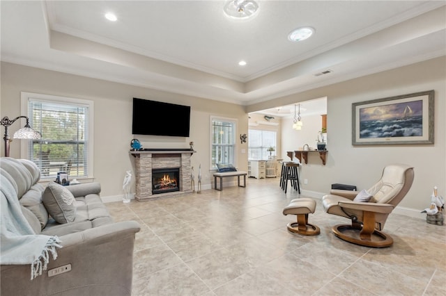 living room featuring a fireplace, ornamental molding, and a raised ceiling