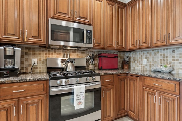 kitchen with tasteful backsplash, appliances with stainless steel finishes, and dark stone counters