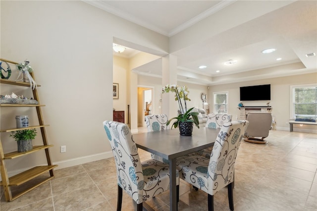 tiled dining space with ornamental molding and a raised ceiling